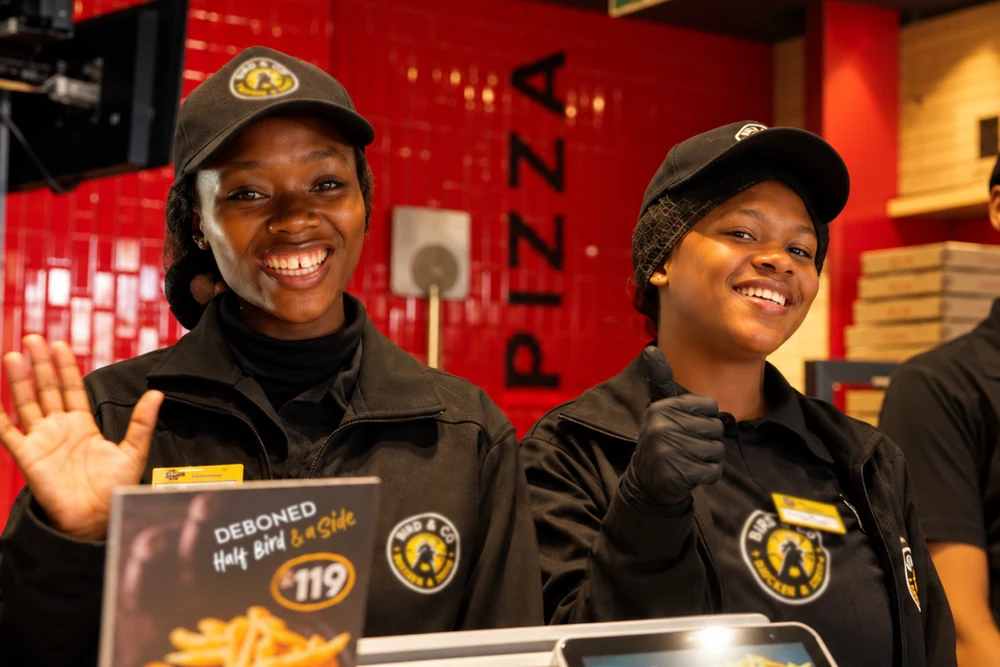 Two smiling Bird & Co team members greeting guests at the counter